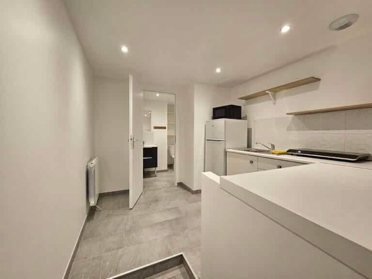 Couloir adjacent à une cuisine lumineuse.